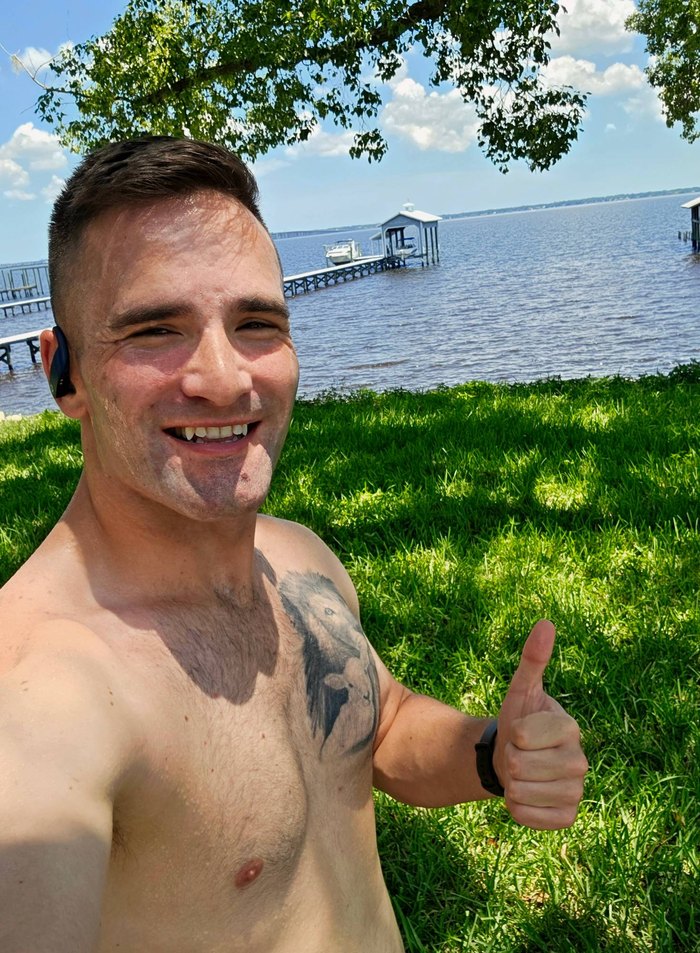 Alex Romano smiling and giving a thumbs up after a run by the water